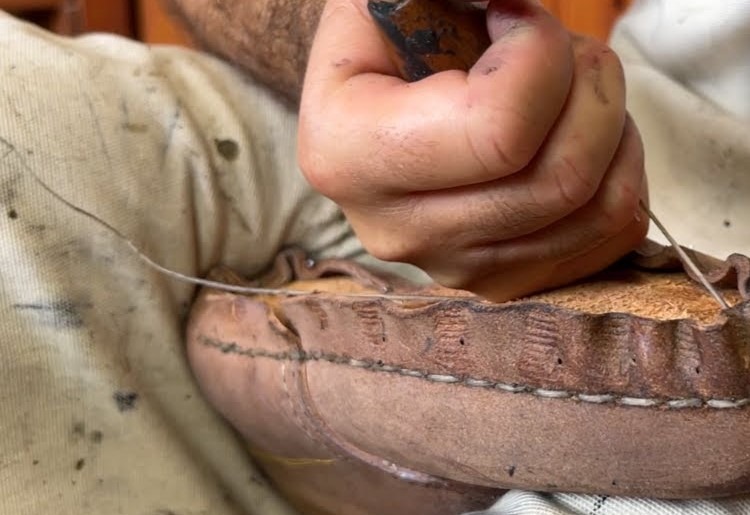 Skilled artisan handcrafting a Moroccan leather bag with traditional designs